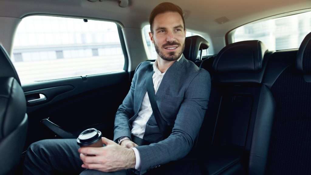 Man enjoying ride with coffee in car.