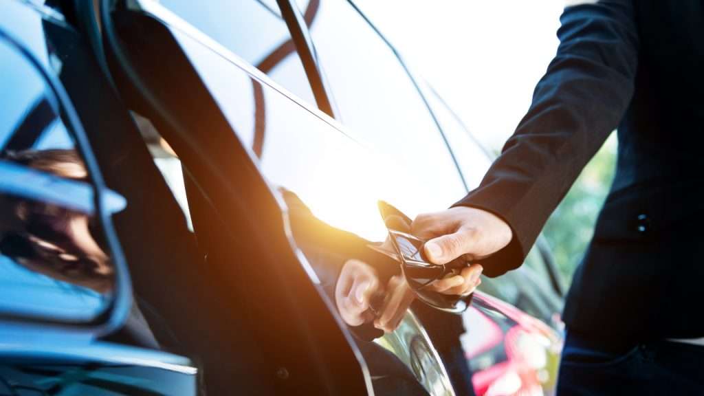 Driver opening car door, comparing Uber vs private chauffeur.