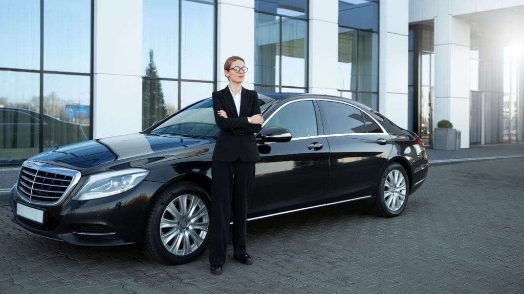 Executive Chauffeur Services chauffeur standing beside luxury car in business attire.