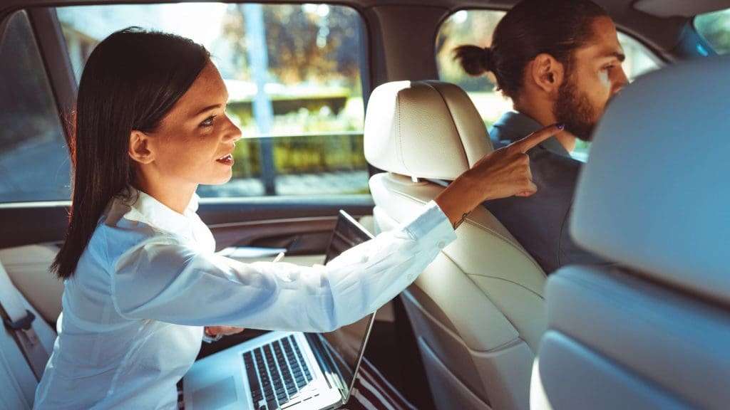 Woman speaking to chauffeur from back seat.