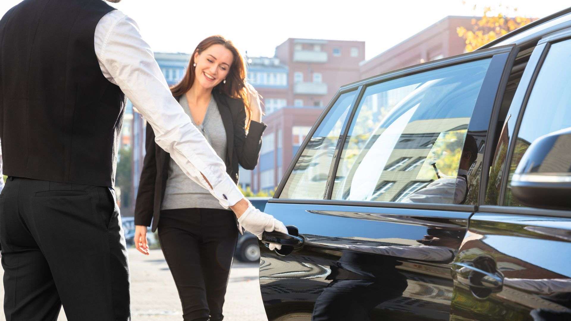 door to door Chauffeur Service : Smiling woman with chauffeur service representatives at her door, ready for assistance.