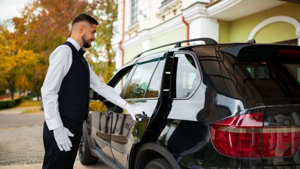 Chauffeur opening car door at luxurious retreat for business class transfers
