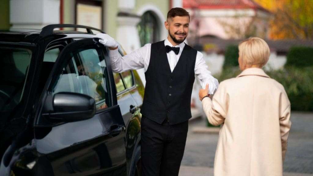 Chauffeur assisting elegant passenger at private event.