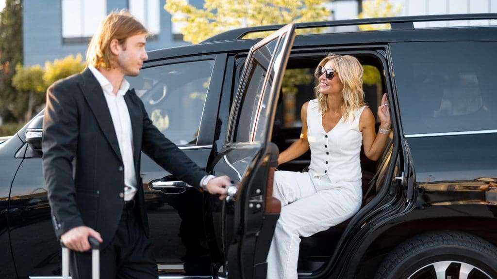 Discover Perth Chauffeurs assisting elegant woman with opening car door in urban setting