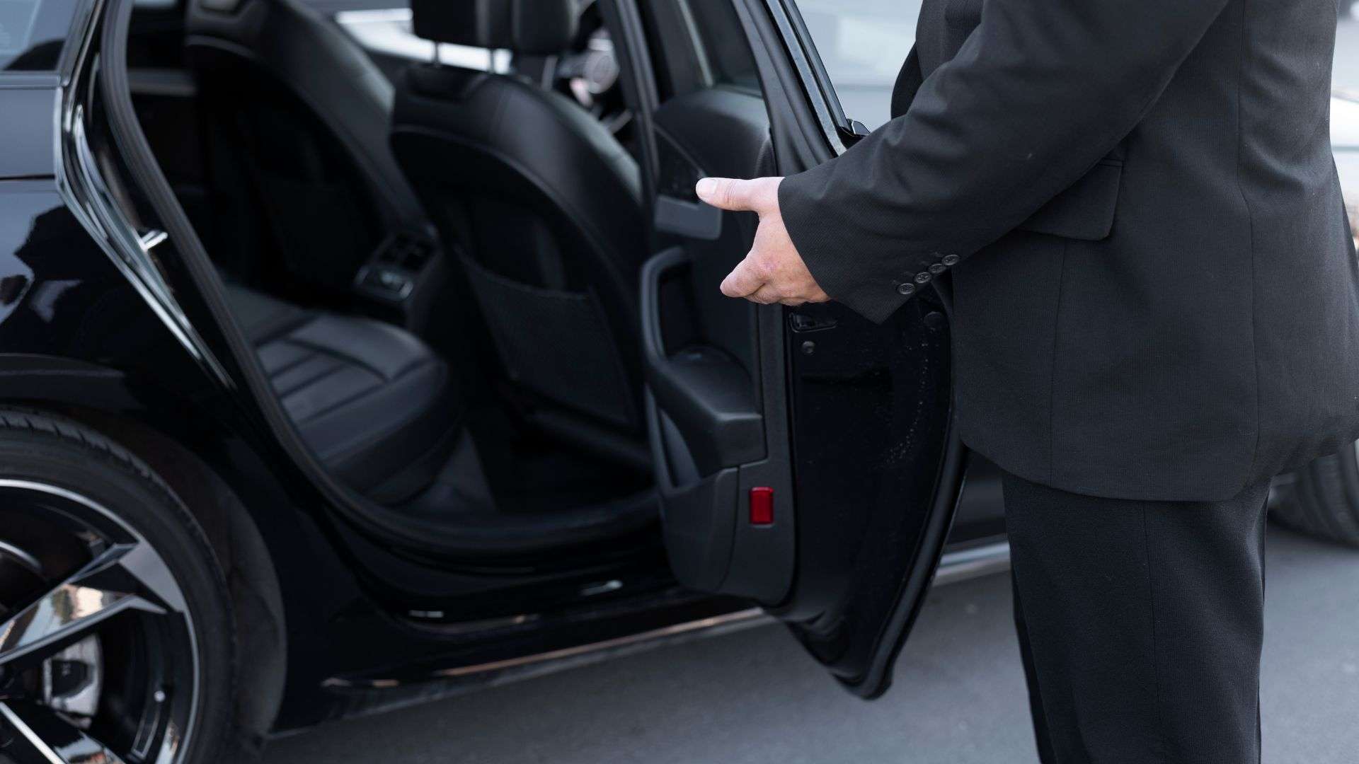Chauffeur Car in Brisbane professional driver in suit opening black luxury sedan door for client on city street